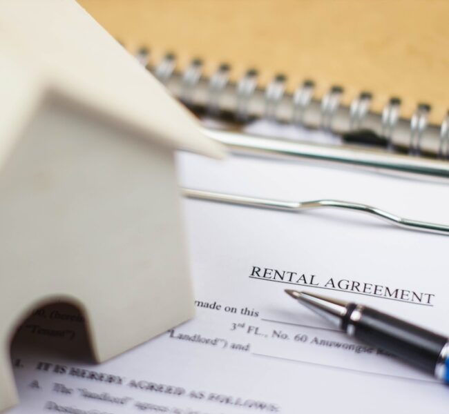 Home model and rental agreement document with pen. Depicts the lease contract process for legal validity.